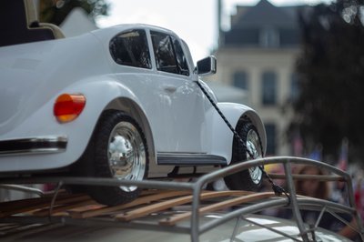 Miniature Volkswagen Beetle model mounted on a classic car roof rack in artistic automotive photography