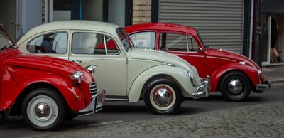 Collection of vintage Volkswagen Beetles parked in an urban street during a classic car meet
