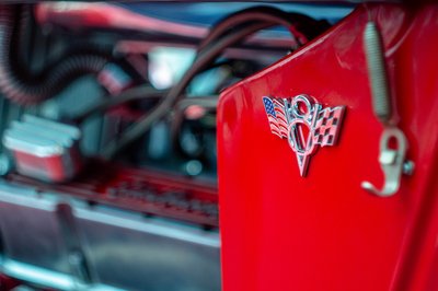 Classic American hot rod V8 emblem detail captured with shallow depth of field and vibrant red paintwork