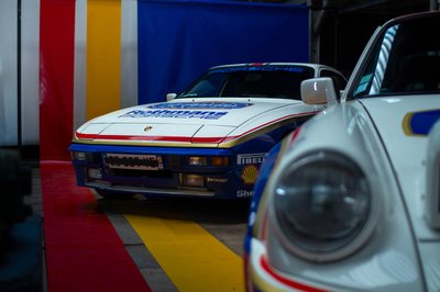 Rothmans Porsche 924 front view alongside Porsche 911 SC, historic rally livery, indoor classic car exhibition photography