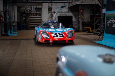 Porsche 908 Esso livery number 35 front view inside historic racing exhibition, Ford GT40 Gulf in background