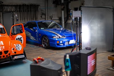 Nissan Skyline R33 GTS-T Platin Tyres drift car beside orange Fun Cup Beetle, indoor automotive event photography